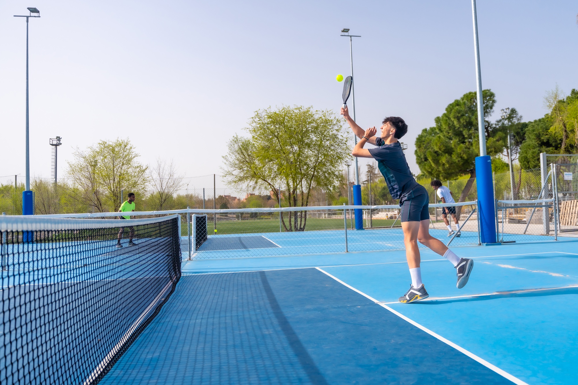 Man jumping while playing pickleball in an outdoor facility